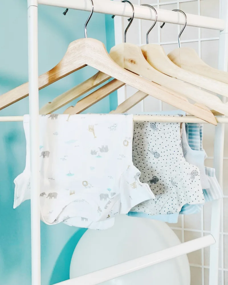 Bodies de bebê estampados pendurados em cabides de madeira
