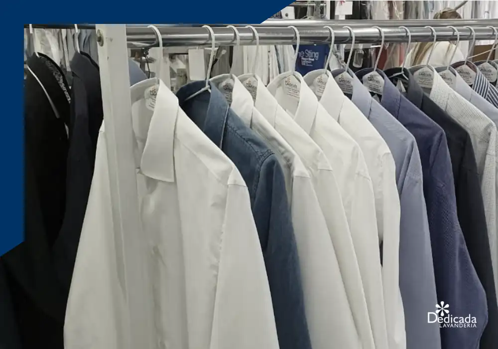 Camisas sociais lavadas e passadas, penduradas em cabides com a etiqueta da Dedicada Lavanderia