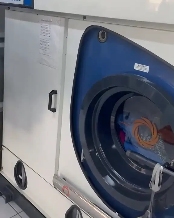 Porta da lavadora a seco Firbimatic, com peças dentro, na produção da Dedicada Lavanderia