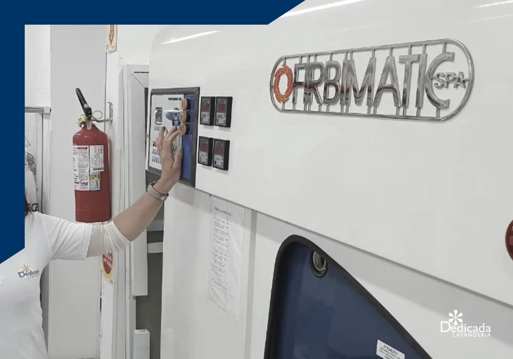 Operadora da Dedicada Lavanderia ajusta o painel da máquina italiana de lavagem a seco Firbimatic