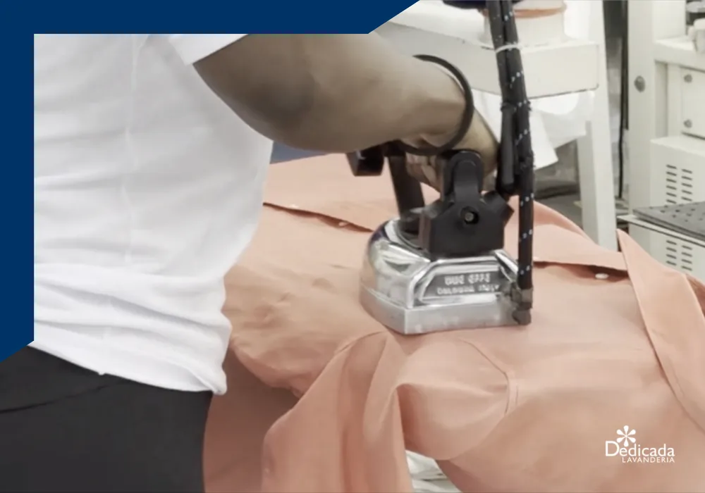 Passadoria à mão com ferro a vapor profissional na banca de passar da Dedicada Lavanderia