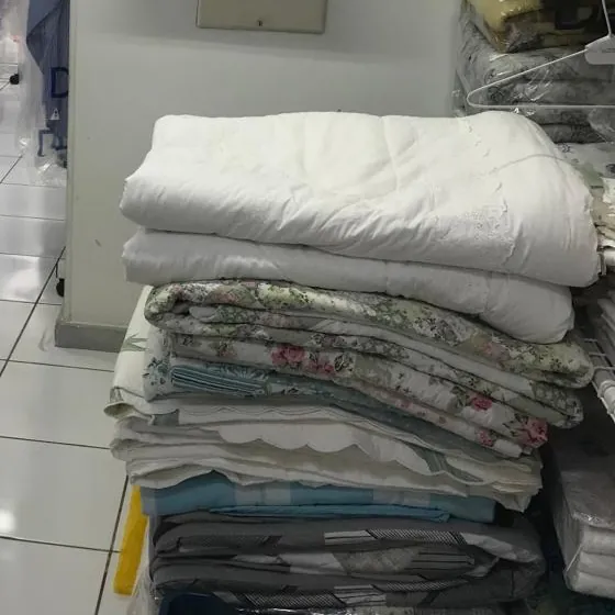 Edredons e jogos de cama dobrados na área de embalagem da Dedicada Lavanderia